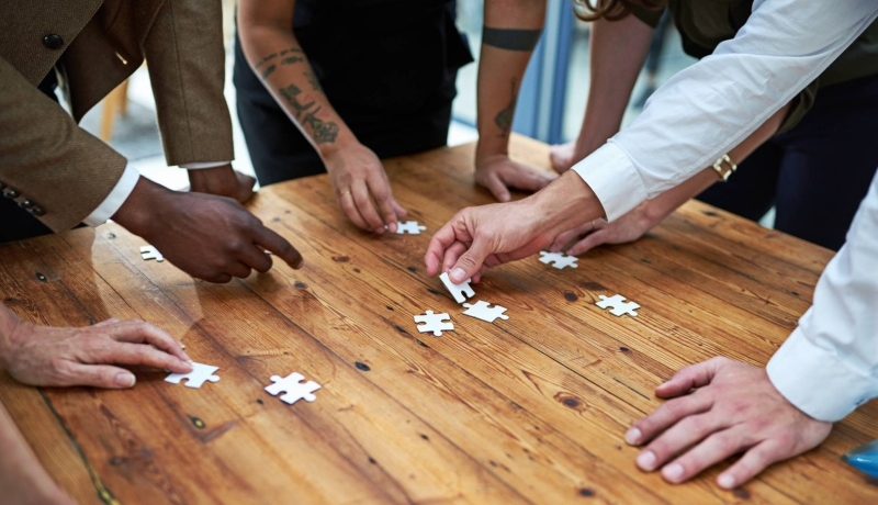 Op een vierkante houten tafel samen een puzzel leggen. Puzzelstukjes, samenwerken, seece