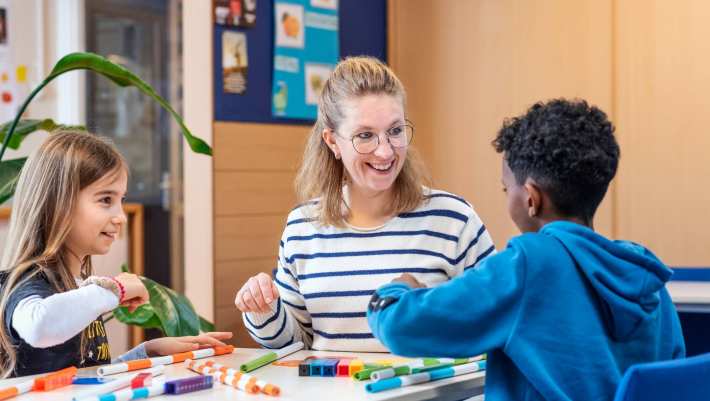 Associate Degree Pedagogisch Educatief Professional met twee leerlingen aan tafel met stiften