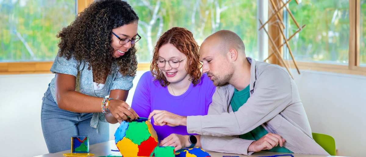 Drie studenten van Leraar Wiskunde maken een bal van puzzelstukken.

