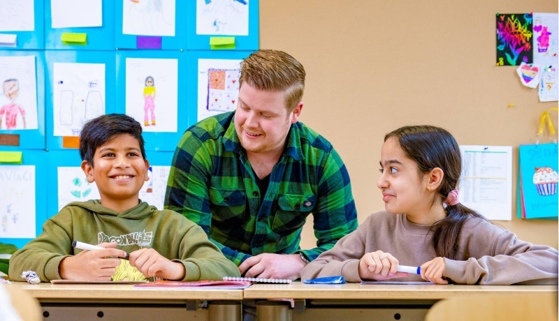 5 kinderen zitten in de klas en steken hun vinger op.