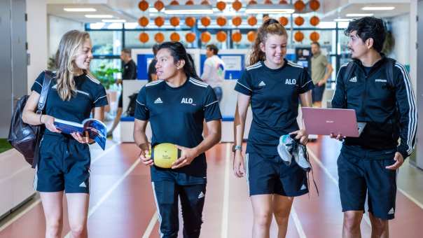 sportkunde en alo samen liggende foto studenten lopen over atletiekbaan binnen bij gymnasion selena esteban carlijn randy 2022