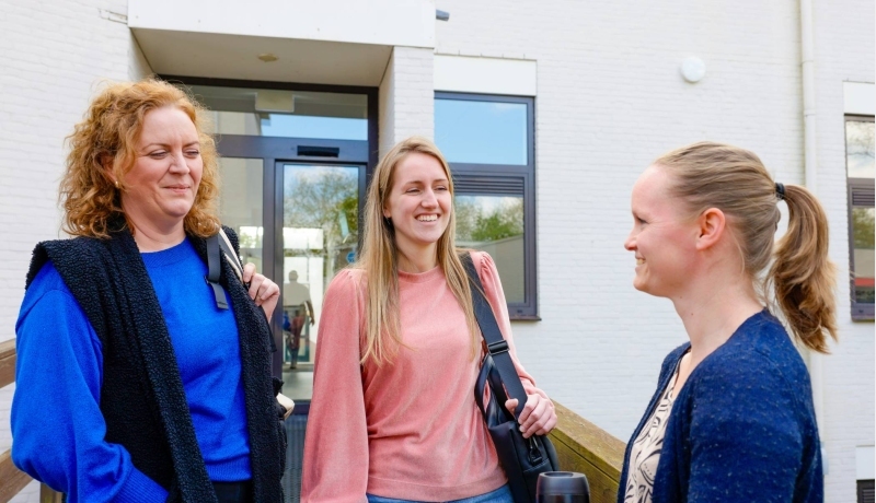 Twee mannen en twee vrouwen staan pratend op de gang