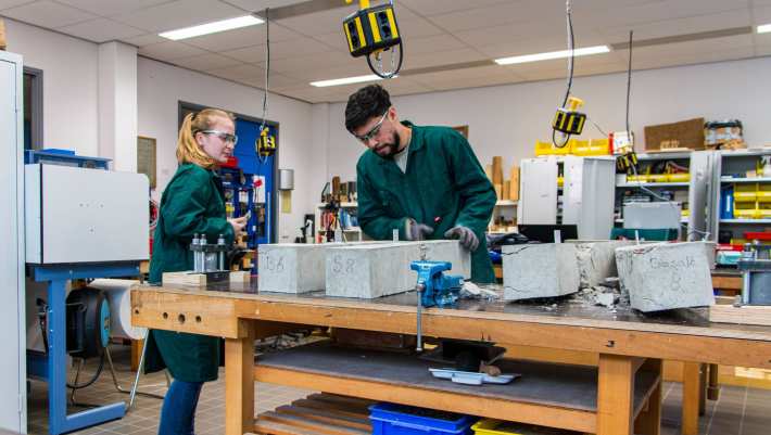 Omscholers naar bouwkunde testen beton in het betonlab.