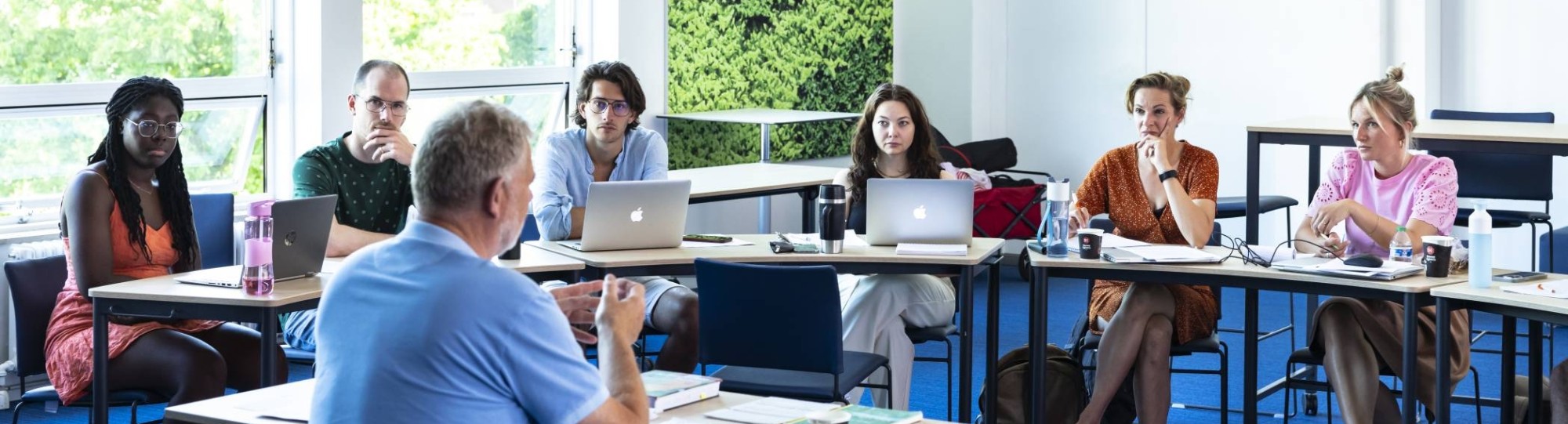 Studenten van de Master Social Work luisteren aandachtig terwijl de docent uitleg geeft.