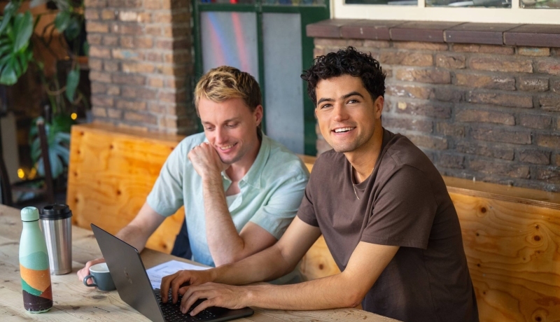 2 hbo masterstudenten werken aan hun laptop.