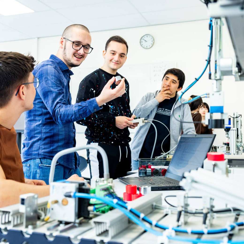 Studenten elektrotechniek krijgen uitleg over een Programmable Logic Controller (PLC).