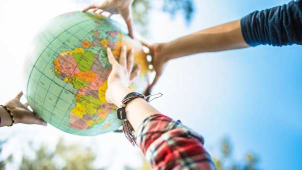 Een groep internationale studenten houdt een wereldbol vast die het internationale karakter van de studie International Social Work voorstelt.