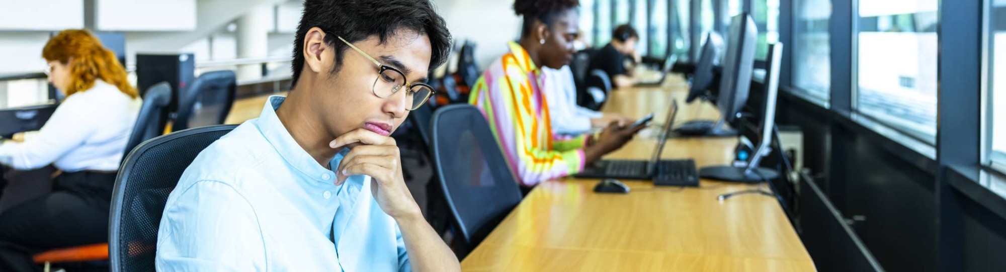 Studenten aan het werk op telefoon of laptop in de bibliotheek.