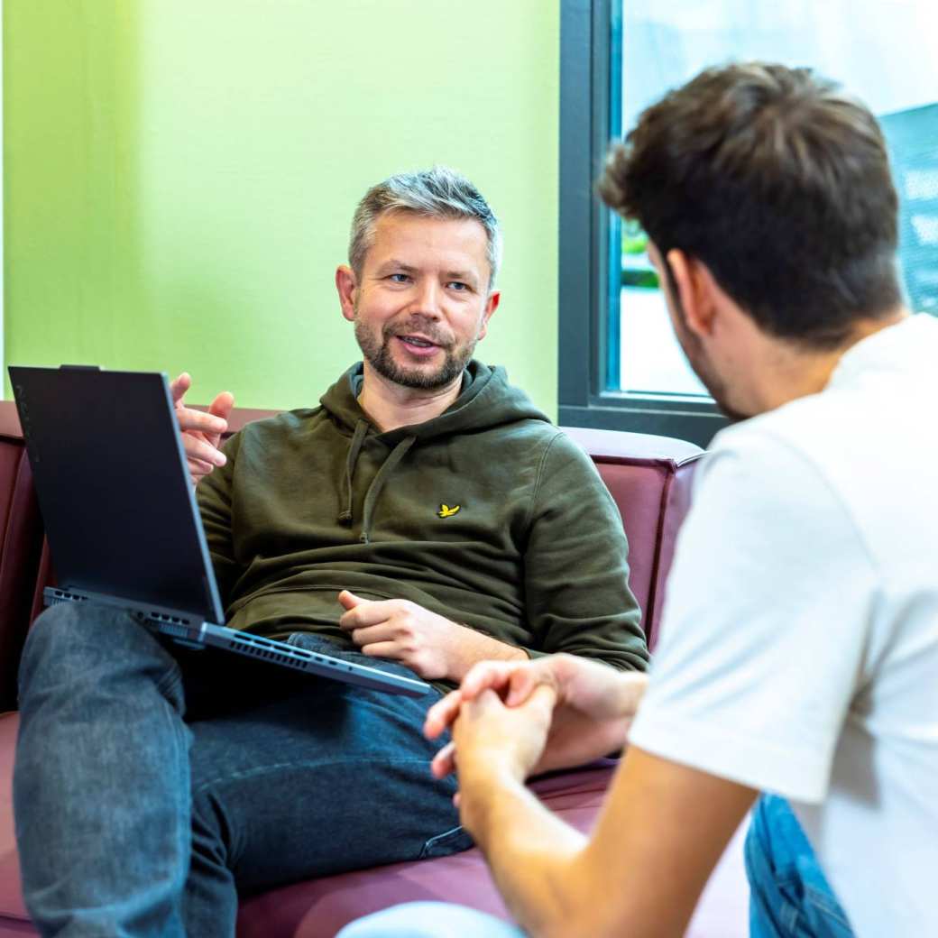 Werkgever vraagt SLIM Scholingssubsidie aan op laptop, in gesprek met werknemer.