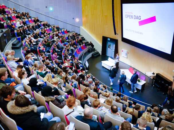 Beeld van bovenaf in auditorium met volle zaal voor presentatie