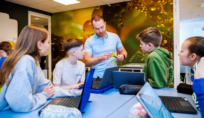Docent Niels Janssen geeft uitleg over een bloem aan 4 leerlingen op het Citadel College. 