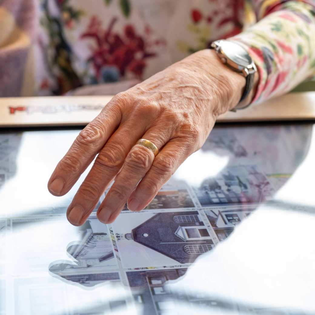 Hand van oudere raakt digitale belevenistafel aan