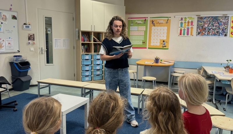 Leerkracht Freek Wouters leest een boek voor aan een aantal leerlingen van groep 3-4
