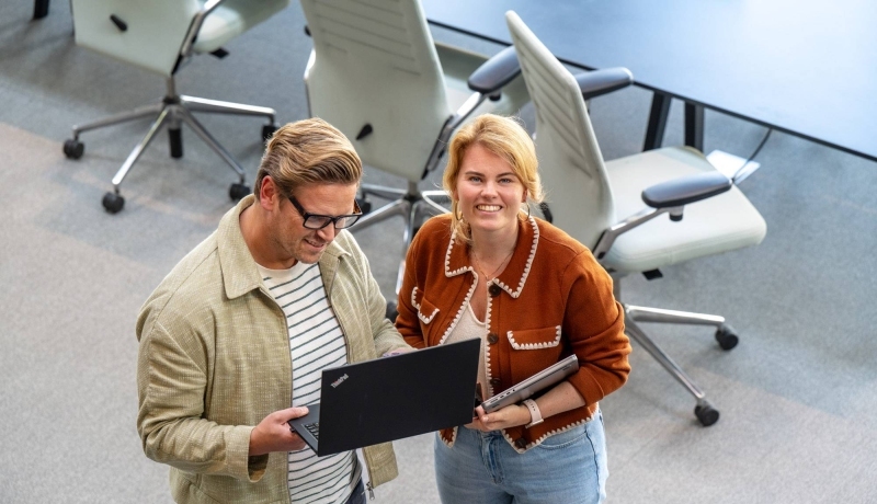 Hbo-masterstudenten bekijken samen informatie op een laptop.