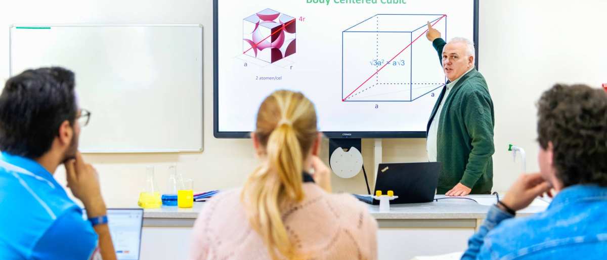 De docent geeft les aan drie studenten
