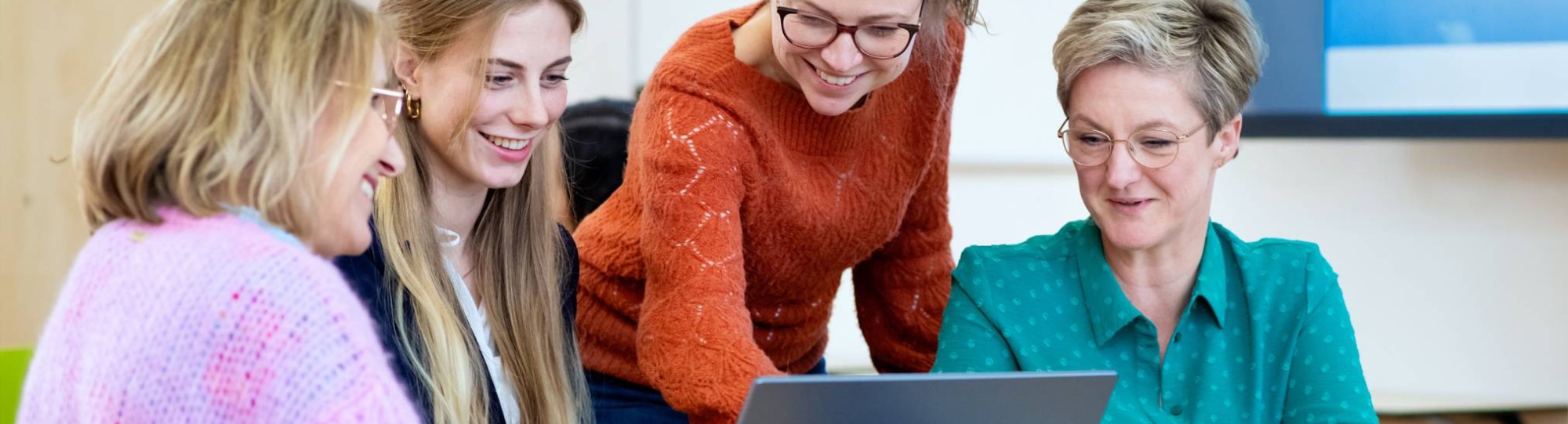 Vier studenten kijken samen naar het scherm (laptop). 