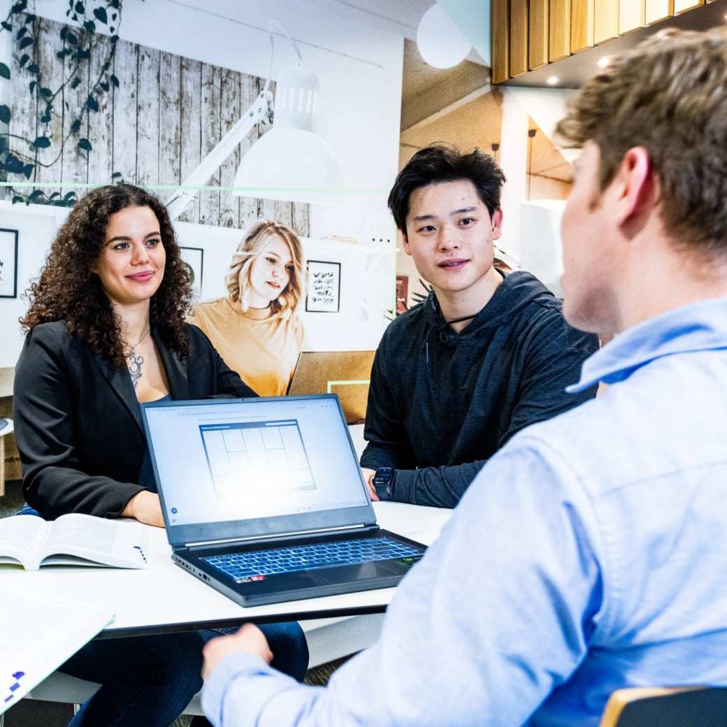 Studenten van Bedrijfskunde voltijd werken samen aan tafel met een laptop erbij