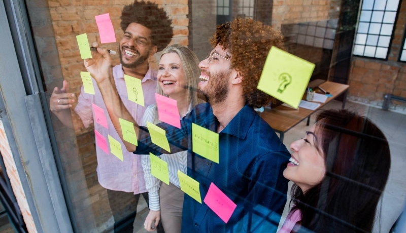 Groep jonge mensen plakken post-its op een glazen wand in een kantoor