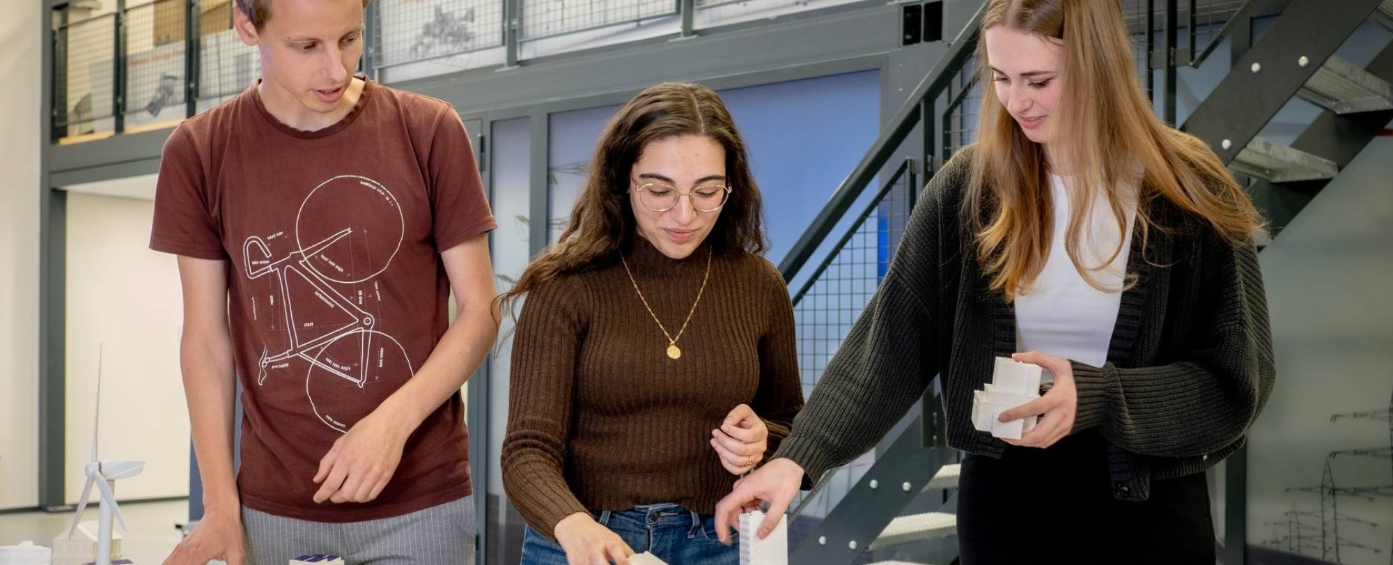 Drie studenten van de Master Engineering Systems Sustainable Energy werken aan de Smart Grid-tafel.