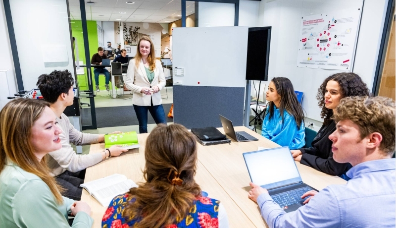 Studenten van de associate degree Bedrijfskunde zitten in de klas en luisteren naar de docent