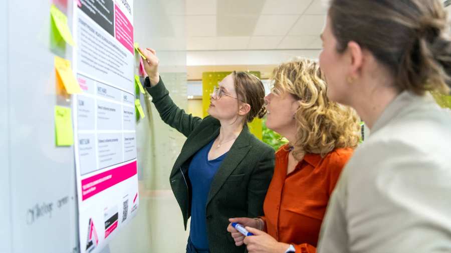 Een man en vrouw in gesprek aan een tafel met een laptop en papieren met visuele informatie