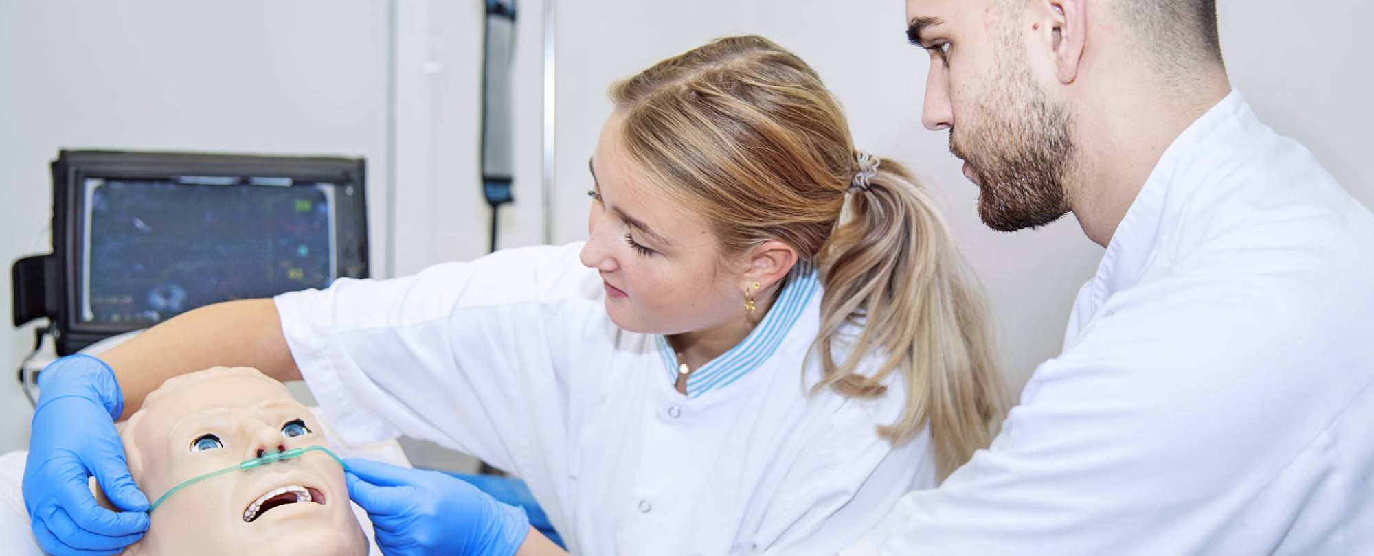 Verpleegkunde studenten aan het bed oefenen beademing bij pop-1