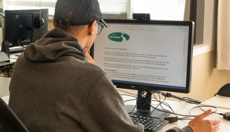 Jongen met pet vult een onderzoek naar overheidsteksten in op een computer in het experience lab