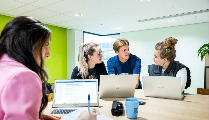 Studenten Human Resource Management (HRM) overleggen in de studio met de laptop erbij