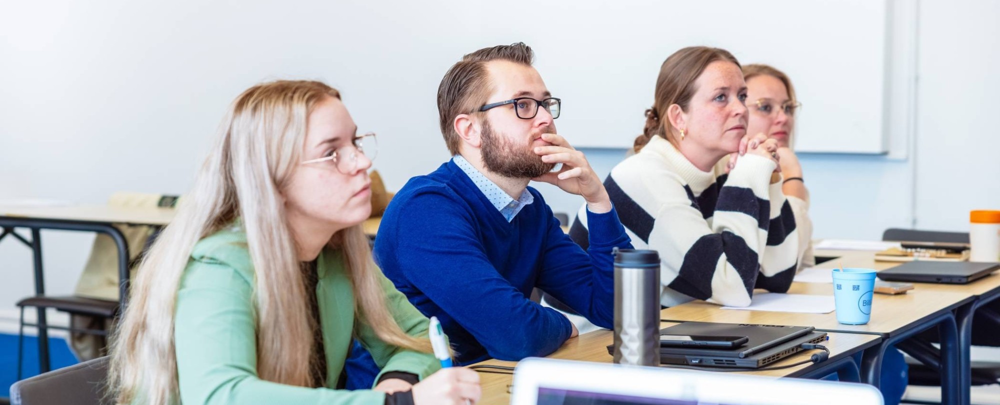 Man en drie vrouwen luisteren naar presentatie. De opleiding maag-, lever-, darmverpleegkundige.