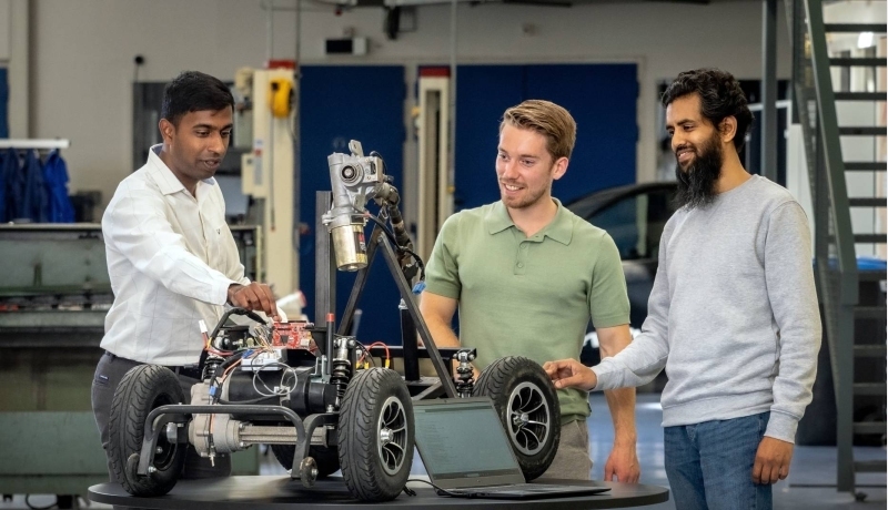 Een docent van de Master Engineering Systems Cyber Physical Systems legt het MORE-project , de scootmobiel, uit aan twee studenten.