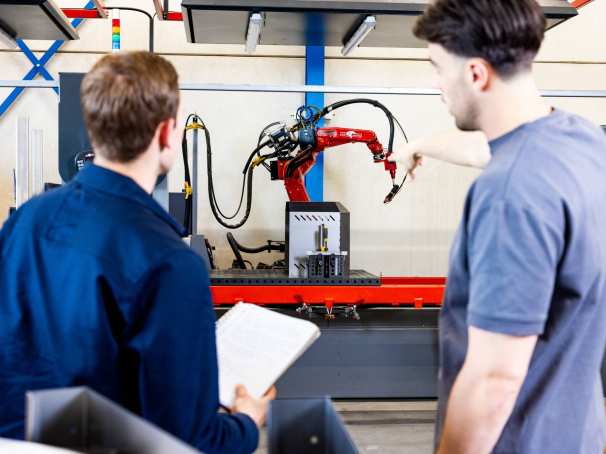 Technische Bedrijfskunde studenten Jort en Derk samen bij robot arm.