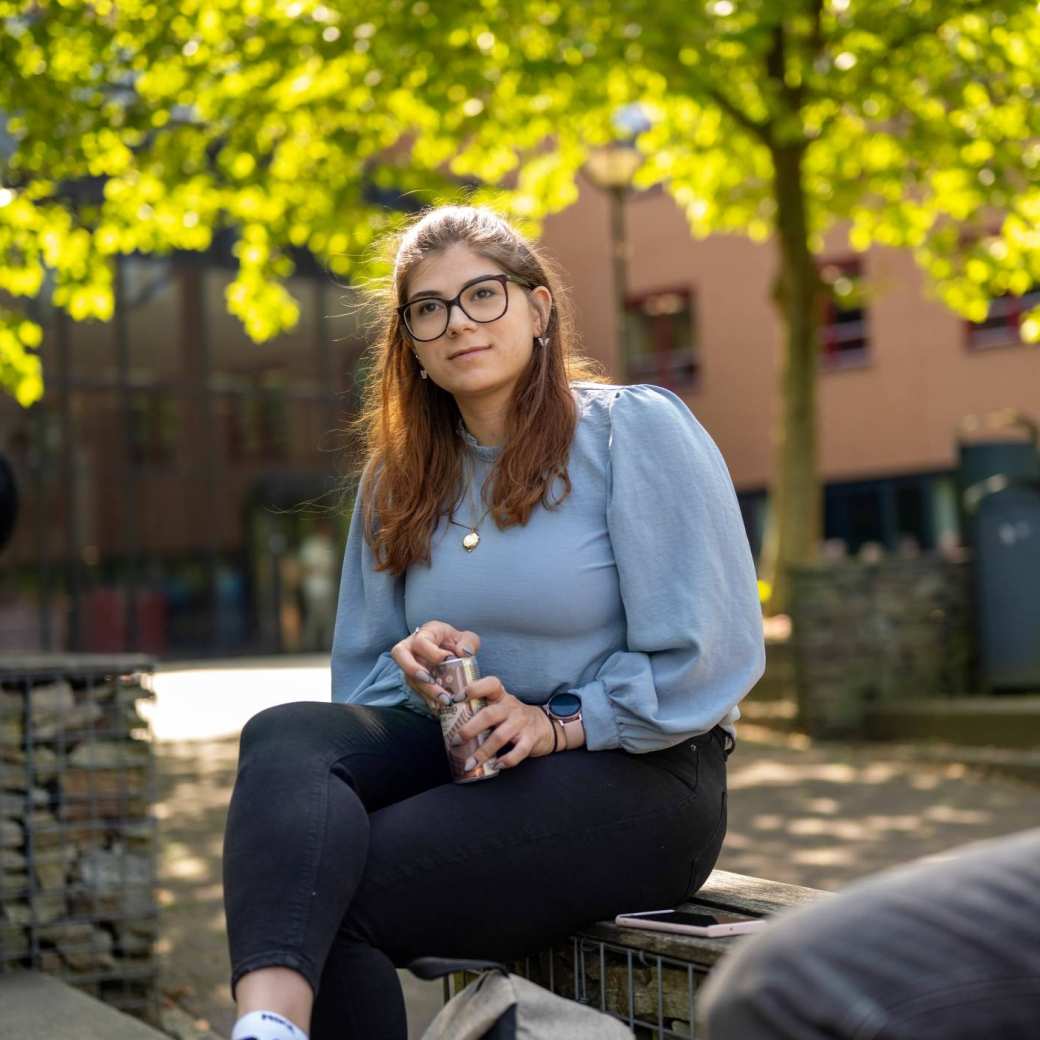 Portretfoto van studente buiten zittend op een bankje bij K33, in de pauze.