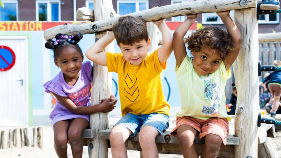 Drie kinderen spelen buiten en hangen aan het klimrek. Foto voor de opleiding leraar basisonderwijs 