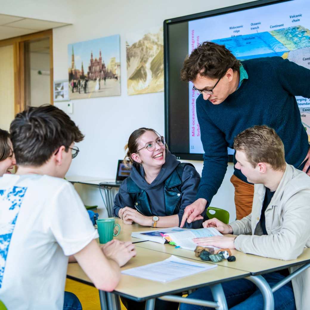 Docent aardrijkskunde legt groepje studenten iets uit