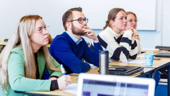 Man en drie vrouwen luisteren naar presentatie. Op de Groenewoudseweg. De opleiding maag-, lever-, darmverpleegkundige.