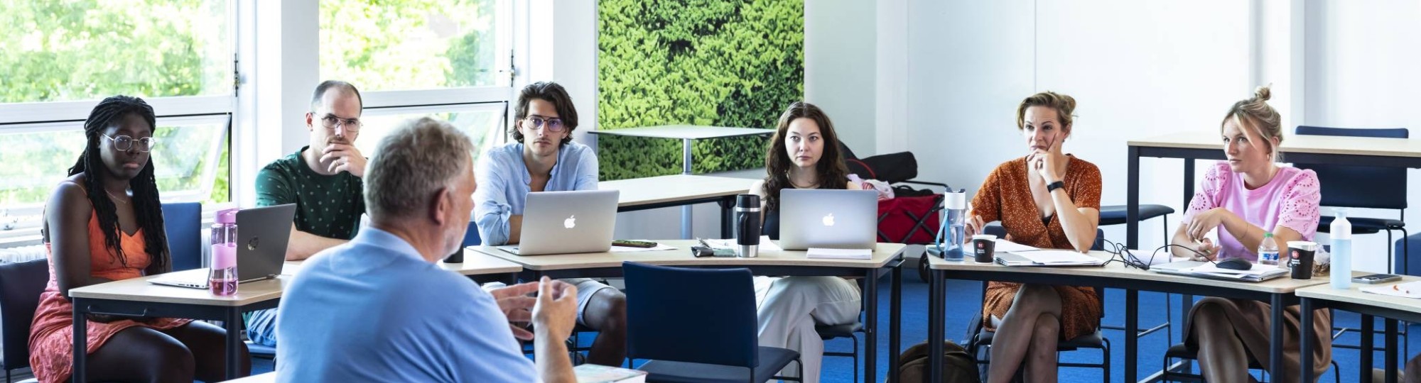 Studenten van de Master Social Work luisteren aandachtig terwijl de docent uitleg geeft.