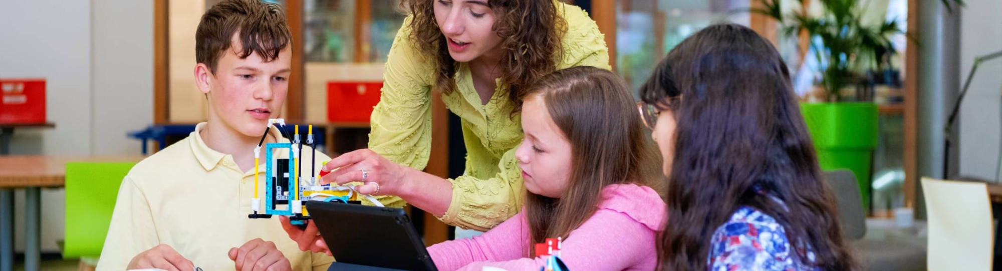 Een student heeft speelgoed vast, terwijl de kinderen toekijken. 