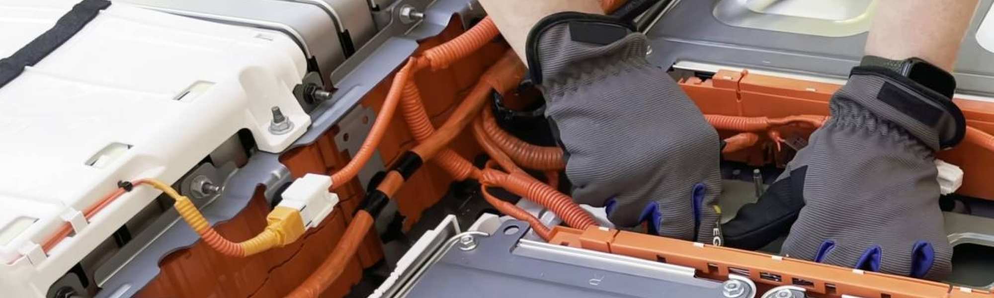 Monteur met blauwe handschoen knutselt aan een grote batterij. Seece - SEE- elektrotechniek, werktuigbouwkunde