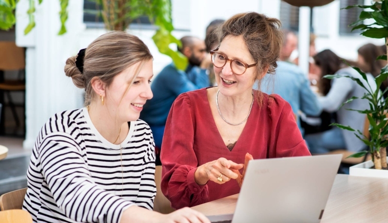 Docent in overleg met student met laptop
