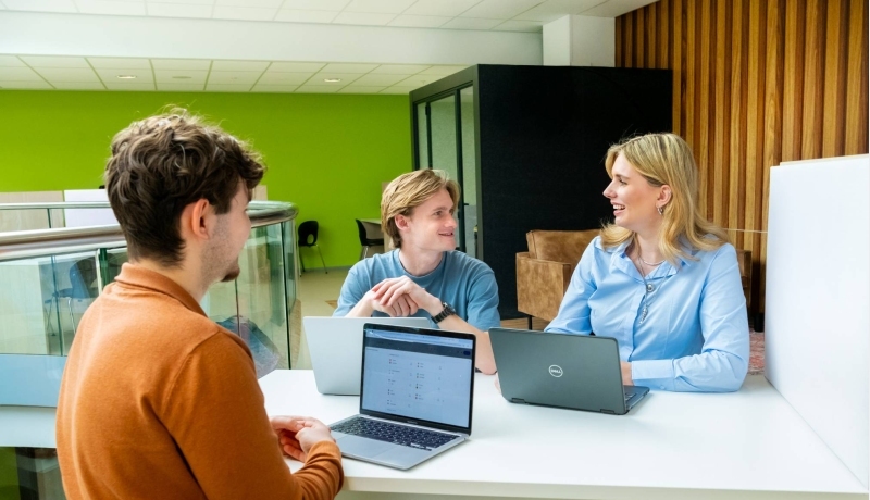 Drie studenten hbo Logistics Management in overleg met laptops erbij