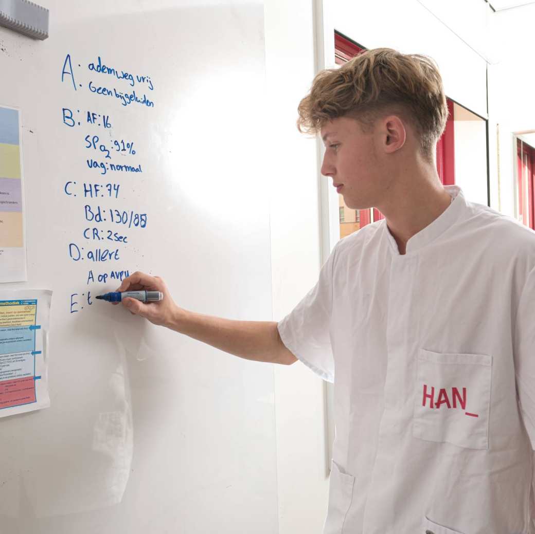 Student MHV schrijft op bord tijdens les