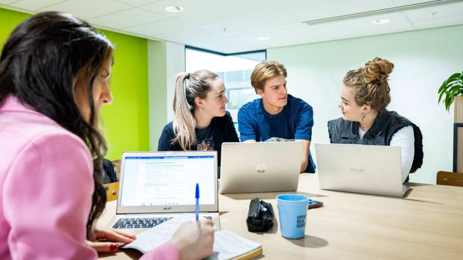 Studenten Human Resource Management (HRM) overleggen in de studio met de laptop erbij
