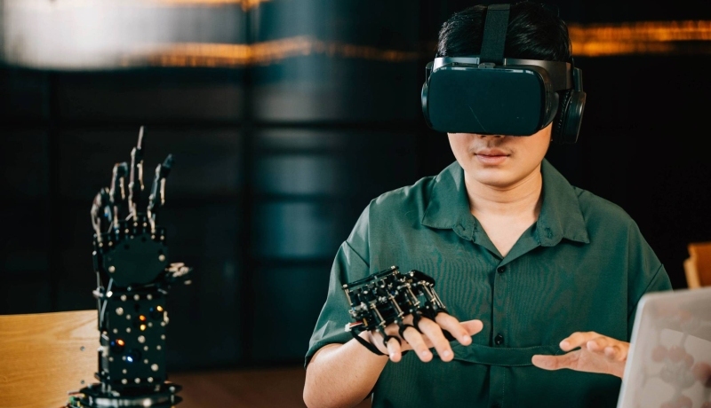 Afbeelding van een jongen met een VR-bril op die een robot hand bestudeert