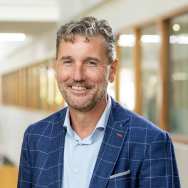 Portretfoto Fred de Jong, blauwe blouse en gemeleerd blauw jasje dragend