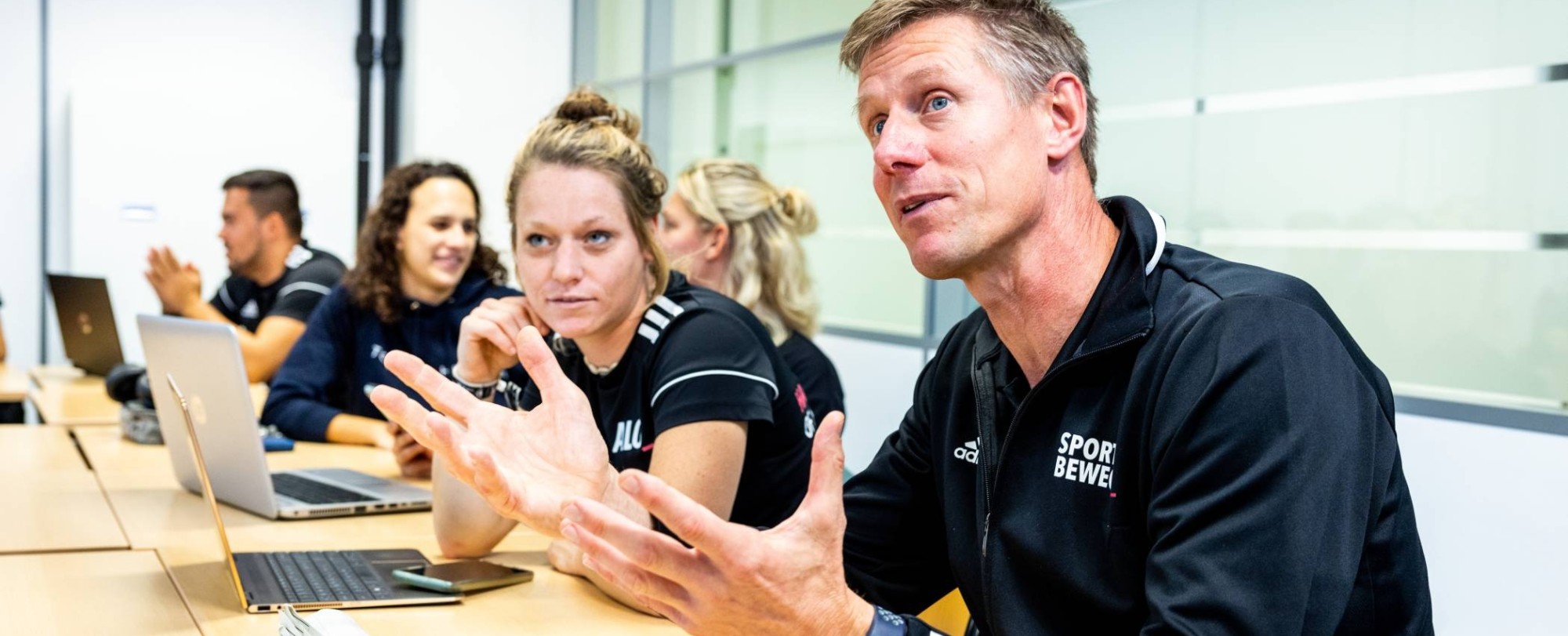 Docent legt uit in de les tussen studenten.