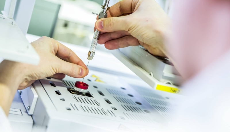 Cursist van Cursus Basiskennis Chemie hanteert injectiespuit in laboratorium.