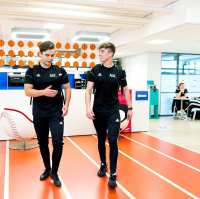 Twee jongens lopen in hun alo-tenue door de gang.