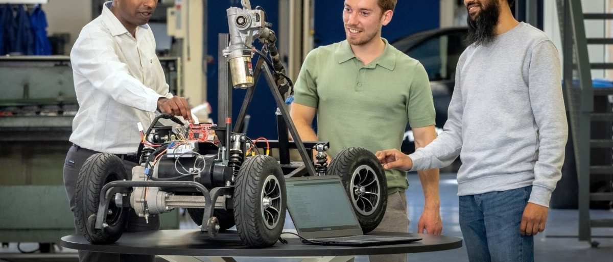 Een docent van de Master Engineering Systems Cyber Physical Systems legt het MORE-project , de scootmobiel, uit aan twee studenten.