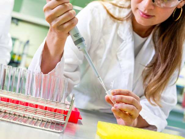 Student in het lab met reageerbuisjes en een pipet