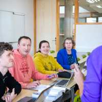 vier masterstudenten luisteren aandachtig naar een docent voor ze